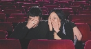 Photograph of two young adults in a movie house hiding their faces with their hands