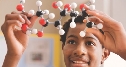 Photograph of a student holding and looking at a model of DNA