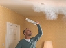 Photograph of a smoke detector on a ceiling with smoke around it