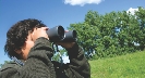 Photograph of a person looking through a pair of binoculars