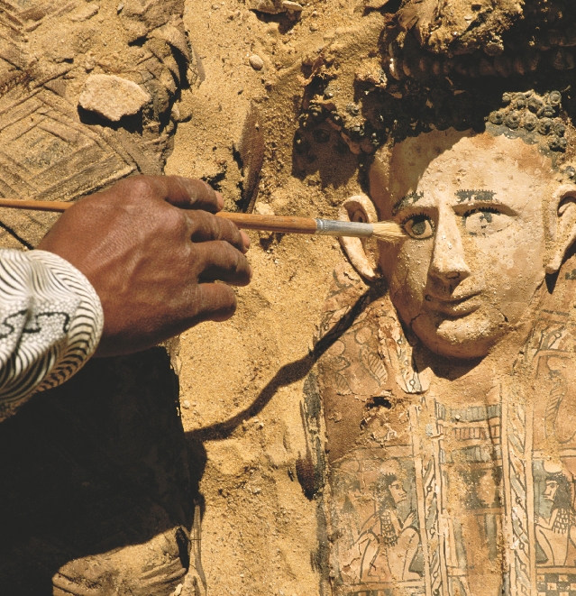 A worker is cleaning the dirt from this ancient Egyptian carving.