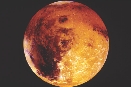 The red-orange color of Mars comes from the rusty soil and dust on its surface.