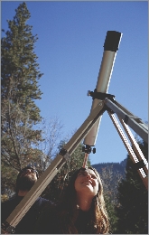 The girl studies the sky through a telescope.