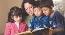 Photograph of a woman reading from a book to children