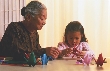 Photograph of an old woman showing a child paper folding (origami)