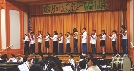 Photograph of students with instruments on a stage in an auditorium