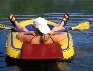 Photograph of a woman in a raft with oars. She is not using the oars.