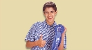 Photograph of a teenage boy with a blue ribbon, smiling and giving the thumbs up sign